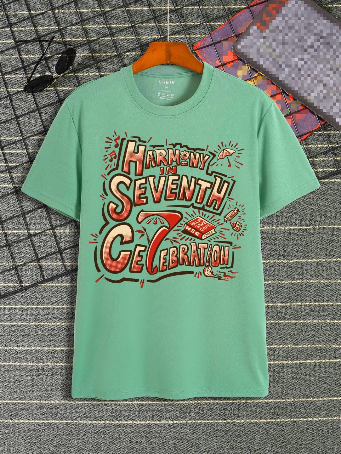 "Kaos berwarna hijau mint dengan desain tipografi meriah bertuliskan 'Harmony in Seventh Celebration', dibuat untuk memperingati ulang tahun ke-7 Payungi dengan semangat Help, Save & Care."